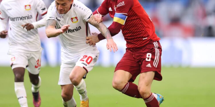 MUNICH, GERMANY - MARCH 05: Robert Lewandowsk of Bayern Munchen tackles with Charles Aranguiz of Leverkusen  during the Bundesliga match between FC Bayern München and Bayer 04 Leverkusen at Allianz Arena on March 05, 2022 in Munich, Germany. (Photo by Alex Grimm/Getty Images)